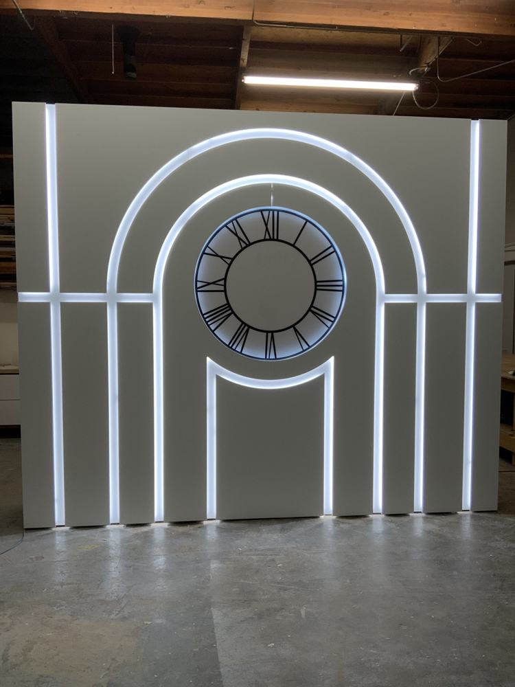 Muro retroiluminado con arco y reloj en el taller